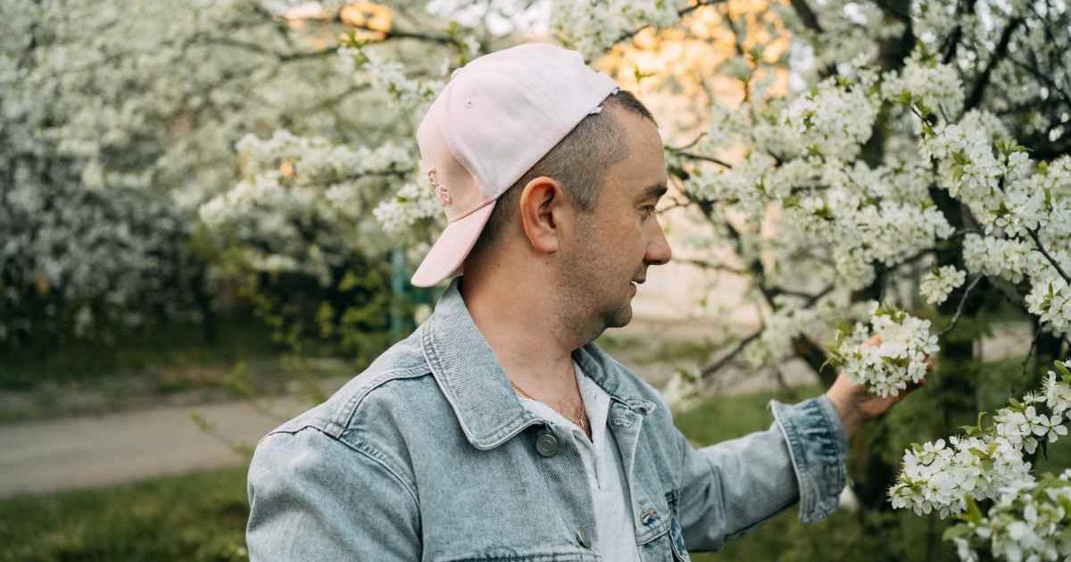 A man admiring a tree with white flowers blooming during springtime. (Representative Cover Image Source: Getty Images | Svetlana Repnitskaya)
