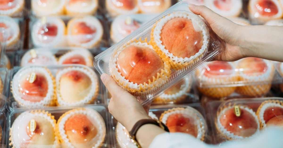 A person picks up a pack of ripe peaches at the store. (Representative Cover Image Source: Getty Images | d3sign)