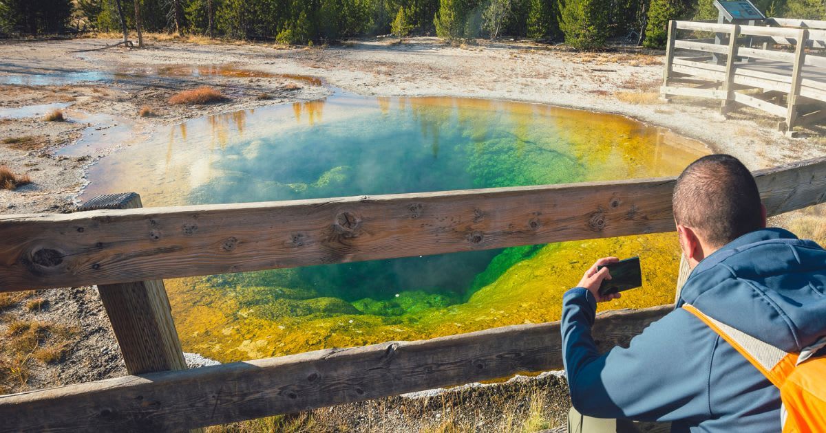 A tourist is capturing a picture of the Morning Glory Pool in Yellowstone National Park. (Representative Cover Image Source: Getty Images | Westend61)