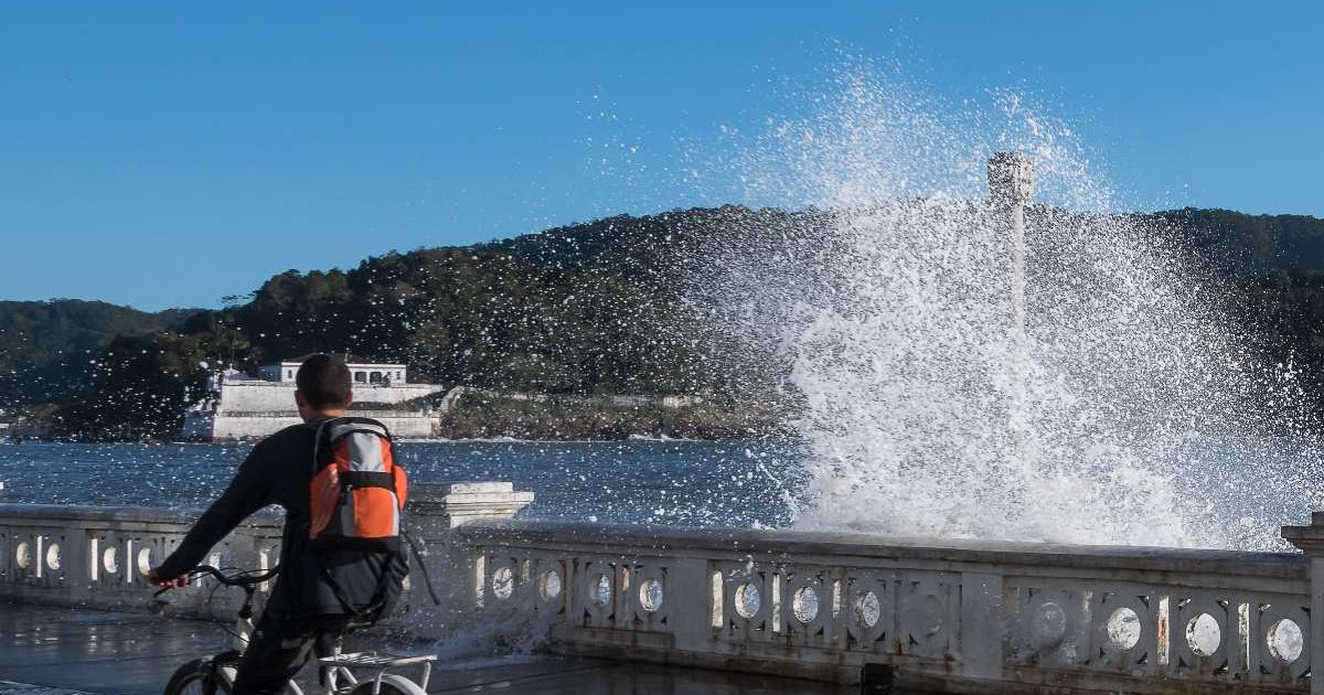 Man riding a bicycle and high tides crashing hard against the beach wall. (Representative Cover Image Source: Getty Images | Stefan Lambauer)