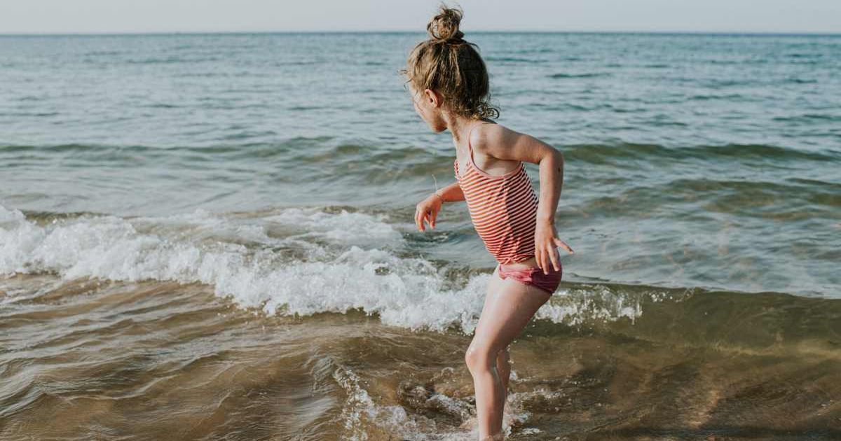 A cute girl running away from the shoreline as waves tower to terrifying heights. (Representative Cover Image Source: Getty Images | Catherine Falls Commercial)