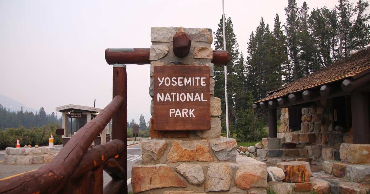 Yosemite National Park sign dangling on a brick structure in front of a hut (Representative Cover Image Source: Getty Images | WillEye)