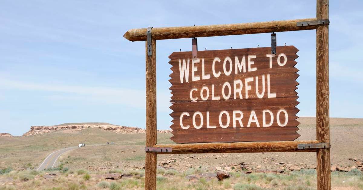 A wooden board reads 'Welcome to Colorful Colorado' on the side of a road. (Representative Cover Image Source: Getty Images | RiverNorthPhotography)
