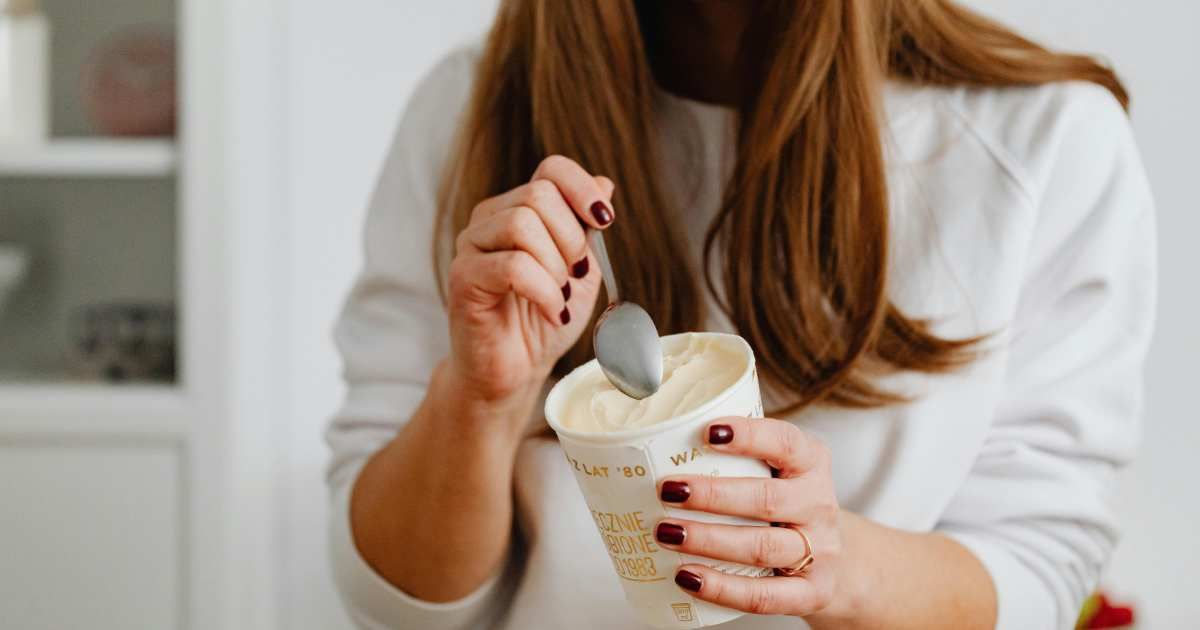 A woman eating a frozen dessert from a tub. (Representative Cover Image Source: Pexels | Kaboompics.com)