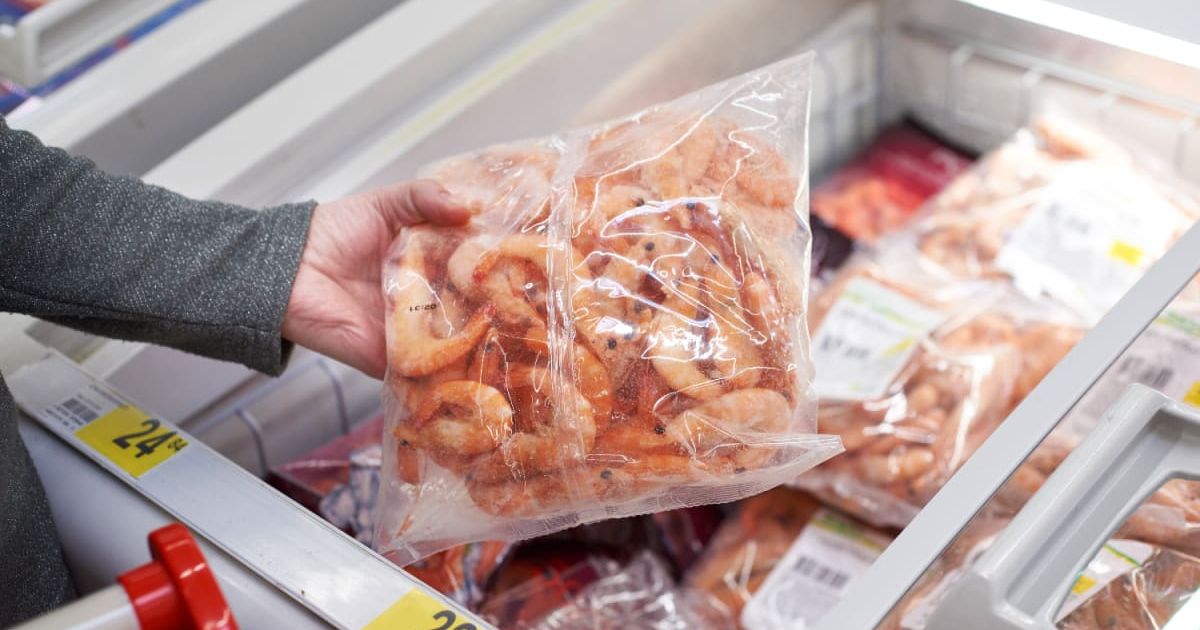 A frozen shrimp packet in hand at a grocery store (Representative Cover Image Source: Getty Images | sergeyryzhov)