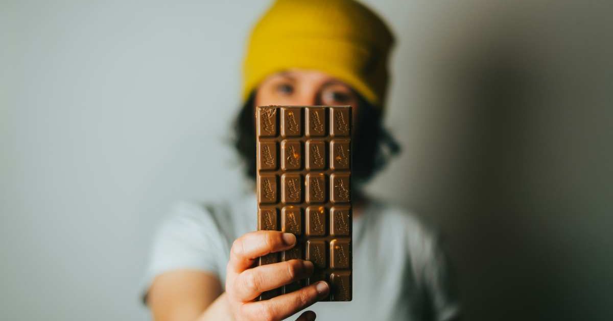 Woman displays a bar of chocolate (Representative Cover Image Source: Unsplash | Tamas Pap)