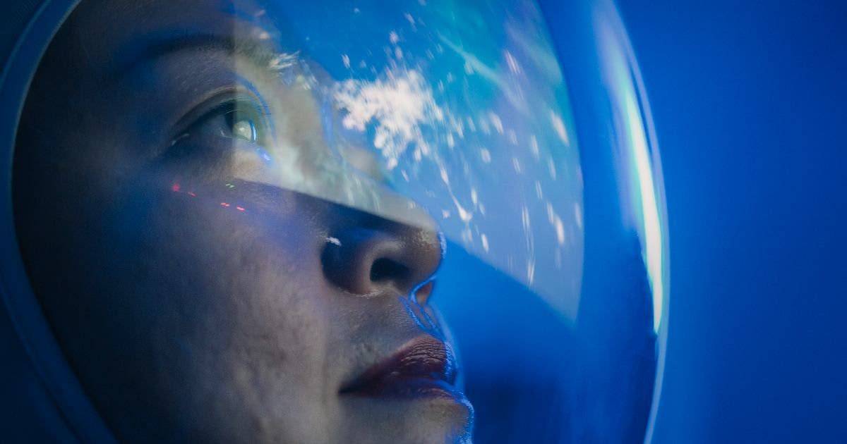 Astronaut looking through the window of a spaceship (Representative Cover Image Source: Getty Images | CG Tan)