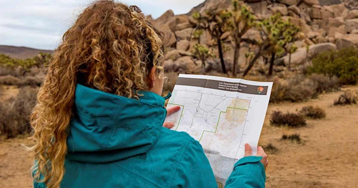 A woman reads a map of America's national park system (Cover Image Source: NPS/Hannah Schwalbe)