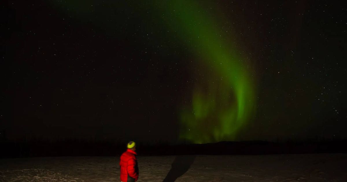 A man watching the Northern Lights. (Cover Image Source: NASA/Rachel Lense)