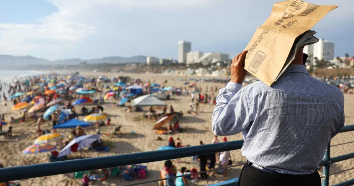 A person uses a piece of cardboard as a sunshade on Santa Monica Pier amid an intense heat wave in Southern California. (Cover Image Source: Getty Images | Mario Tama)